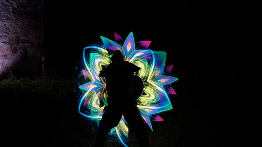 Amaterasu-Artist mit leuchtenden LED-Tools auf dunkler Bühne