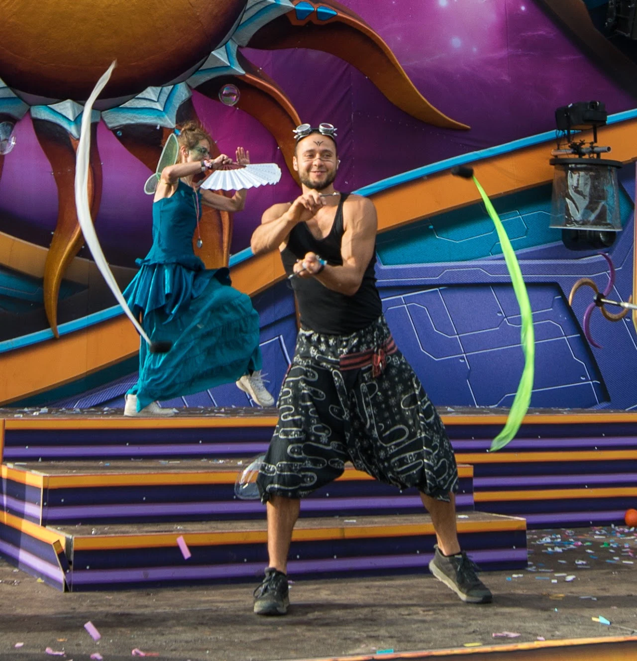 Kostümierter Flowarts-Artist mit farbigen Tools bei einem Festival am Tag